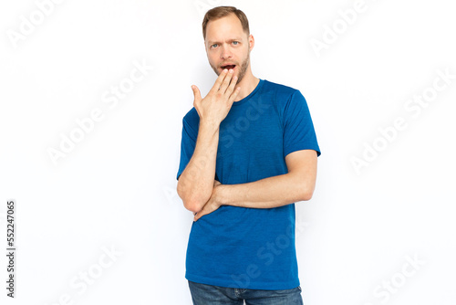 Shocked man covering his mouth with hand. Bearded Caucasian man receiving excited news while standing on white background and looking at camera. Shock, secret, amazement