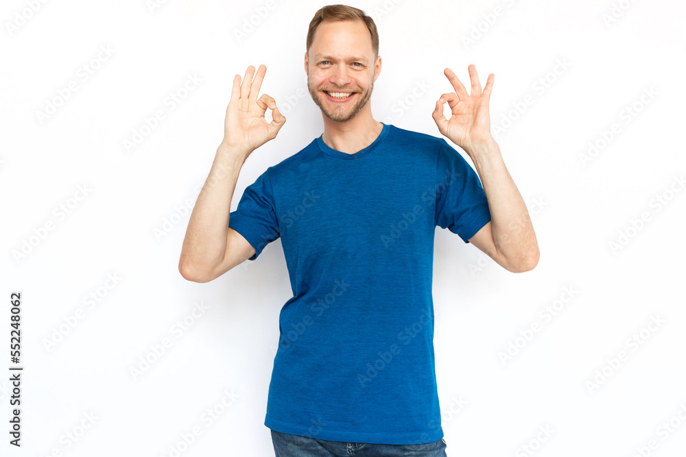 Caucasian man smiling and showing OK gestures at camera. Happy male adult looking at camera on white background, posing for camera. Satisfaction, success, agreement concept Caucasian man smiling and showing OK gestures at camera. Happy male adult looking at camera on white background, posing for camera. Satisfaction, success, agreement concept