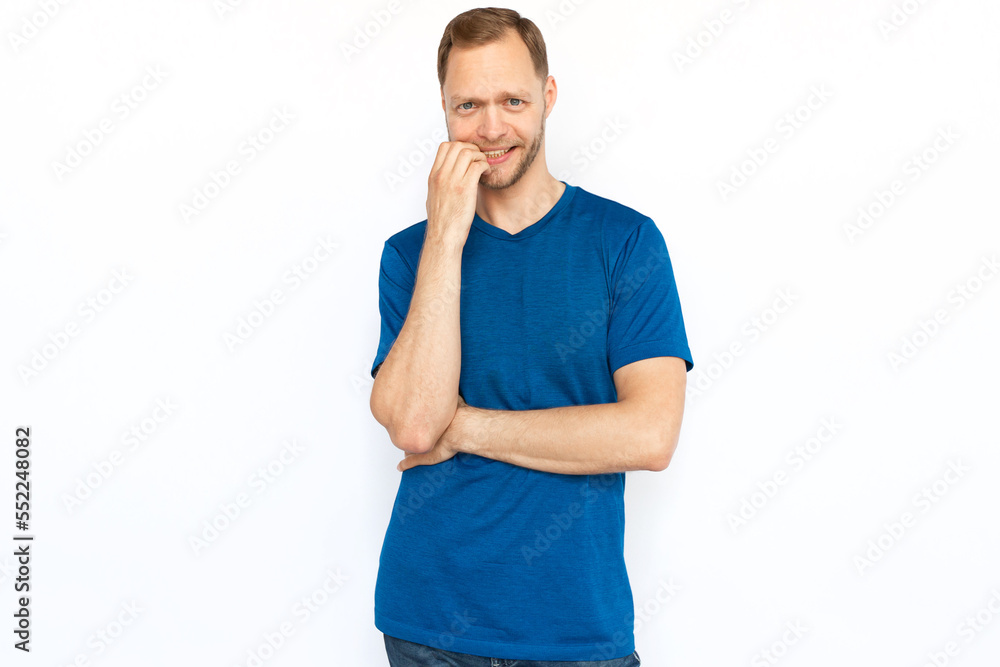 Nervous man biting his nails while standing on white background. Concerned Caucasian man looking at camera, feeling stressed and worried. Stress, anxiety, fear concept Nervous man biting his nails while standing on white background. Concerned Caucasian man looking at camera, feeling stressed and worried. Stress, anxiety, fear concept