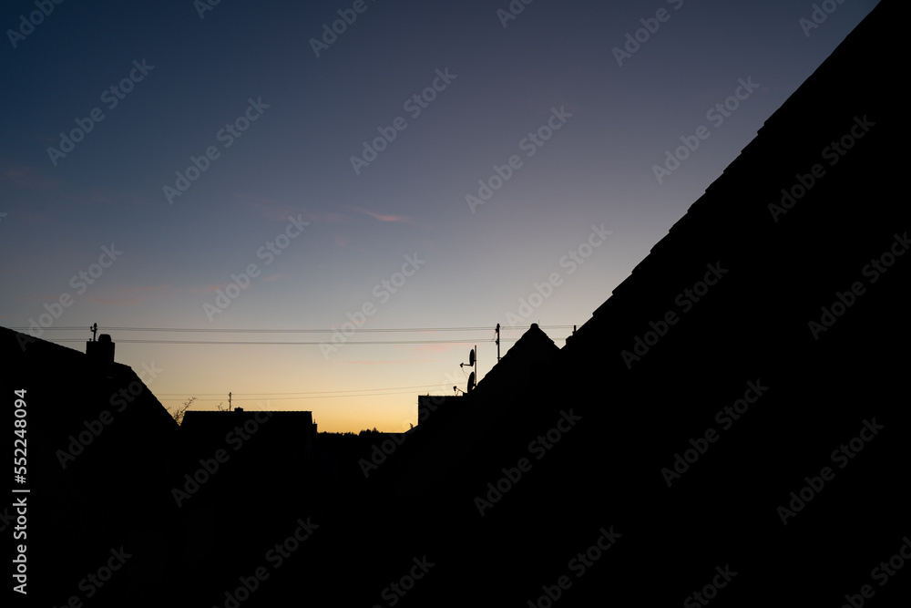 Silhouette of house roofs on a summer evening as the sun goes down