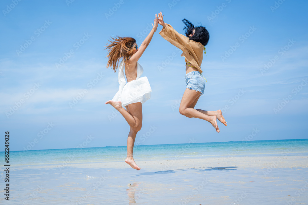 Fototapeta premium Two attractive girls jumping on the beach,Having Fun,Summer Lifestyle.