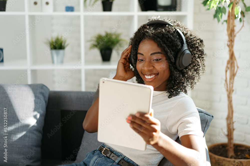 Young african woman using digital tablet and smiling while resting at home. Young african woman using digital tablet and smiling while resting at home.