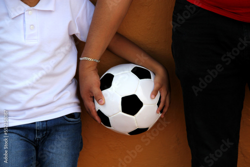 Latino dad and son share their love for soccer, they take a ball with their hands excited to watch the football game © Arlette