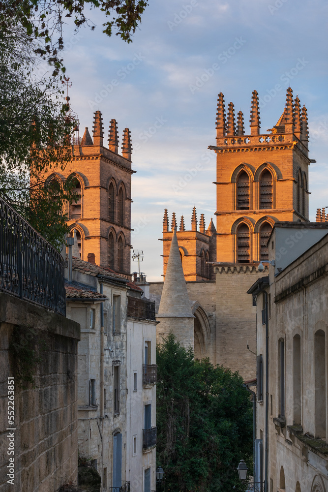 Landscape view at sunset of ancient historic landmark St Pierre or St Peter's cathedral bell towers through narrow street, Montpellier, France