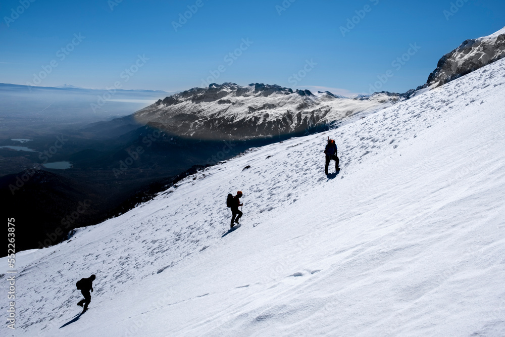 mountaineers climb to the summit together on a difficult and steep slope