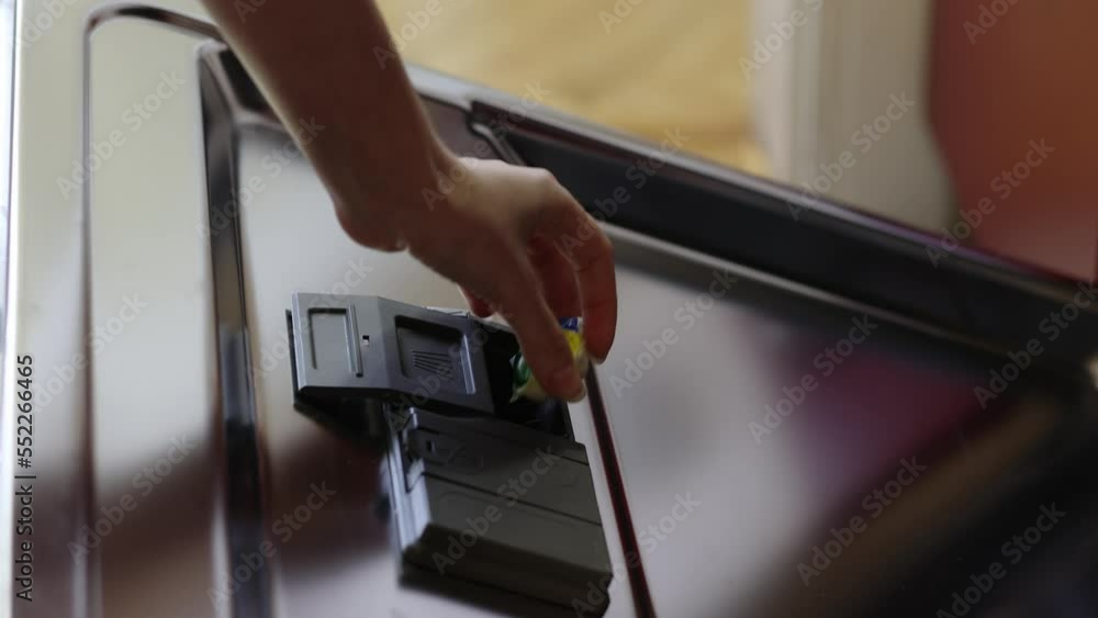 Woman's hand puts tablet for washing dishes in dishwasher. Close-up. Automatic dishwashing machine at home. Woman's hand puts tablet for washing dishes in dishwasher. Close-up. Automatic dishwashing machine at home.