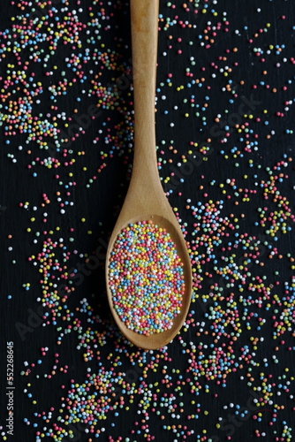 Sugar sprinkles in a spoon on a black background
