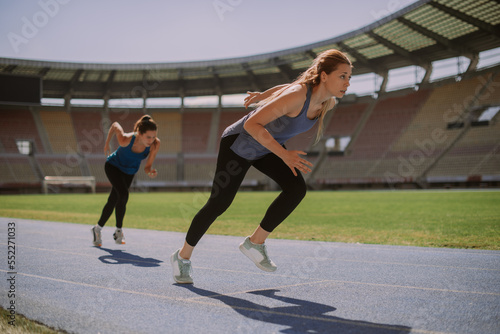 Pretty girls running on a blue sports track