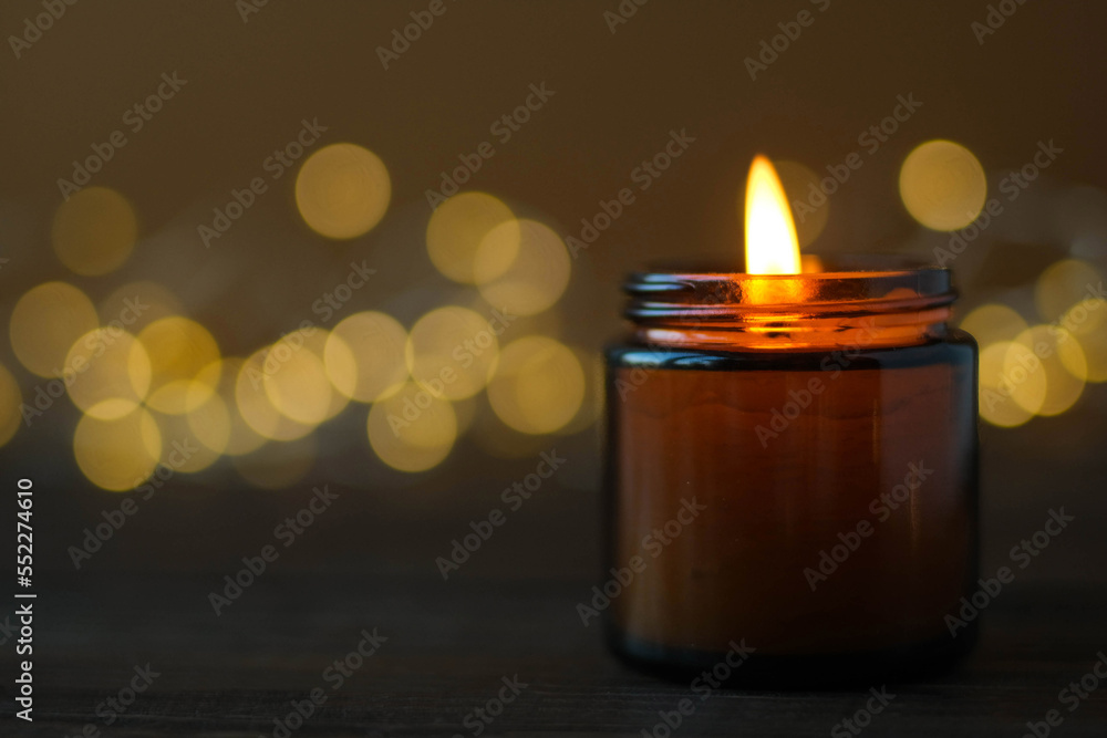 Close-up burning candle in a brown glass with selective focus on golden bokeh background Close-up burning candle in a brown glass with selective focus on golden bokeh background