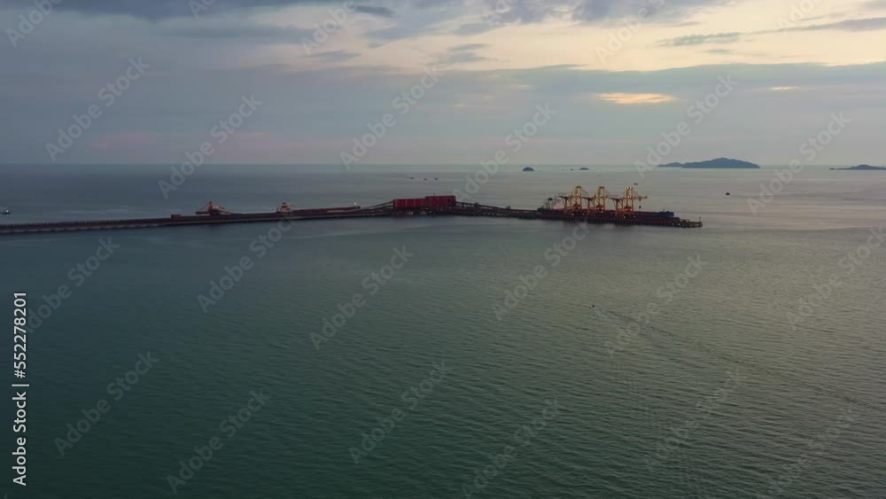 Aerial drone flyover straits of malacca, sea in west coast Malaysia capturing the export wharf of brazilian vale iron ore mining corporation, logistic bulk terminal jetty along the horizon at dusk. Aerial drone flyover straits of malacca, sea in west coast Malaysia capturing the export wharf of brazilian vale iron ore mining corporation, logistic bulk terminal jetty along the horizon at dusk.