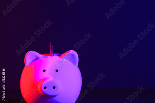 Piggy bank on a dark background with coin and red-purple backlight. Banking concept. Bright neon lights