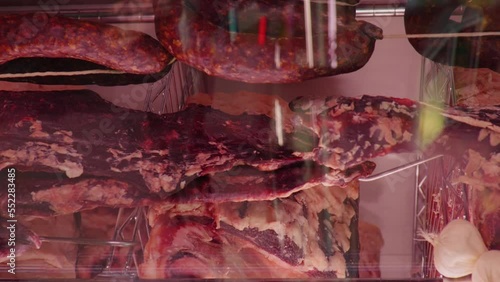 Vertical Screen: Slices of dried or smoked beef meat along with types of sausages in dry ading cabinet. Dry-aged cuts of raw meat. Food manufactoring. photo