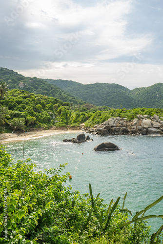 Sunny view of Carbo San Juan Beach in Tayrona national park, South America, Columbia. Some rocks in the warm ocean at a lagoon near Santa Marta. Vibrant and green jungle