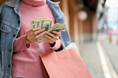 Gorgeous and rich woman counting her cash while shopping at the shopping mall. cropped image