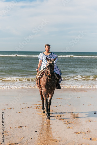 beautiful woman wearing traditional costume and riding a horse on the sea background, entertainment concept