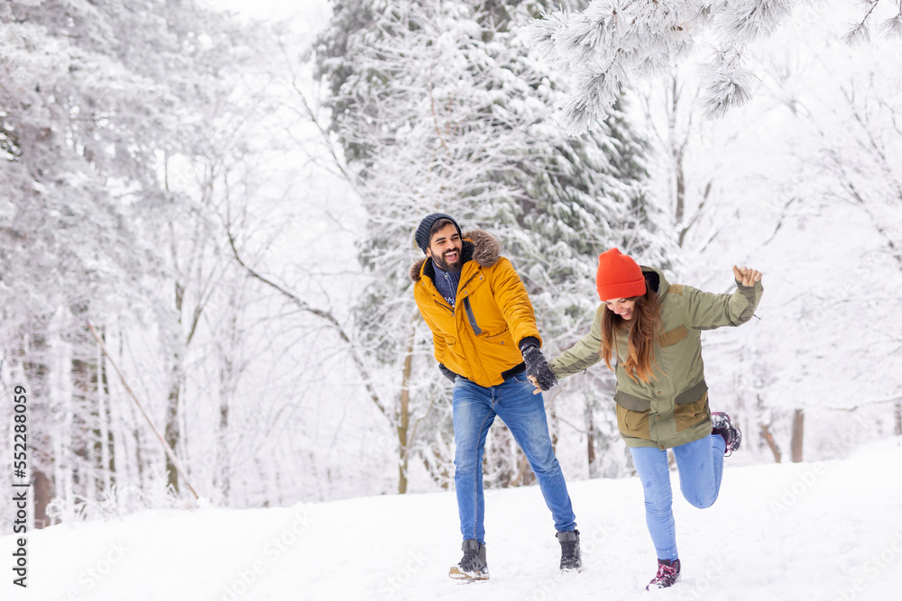 Couple having fun running in the snow while on winter vacation