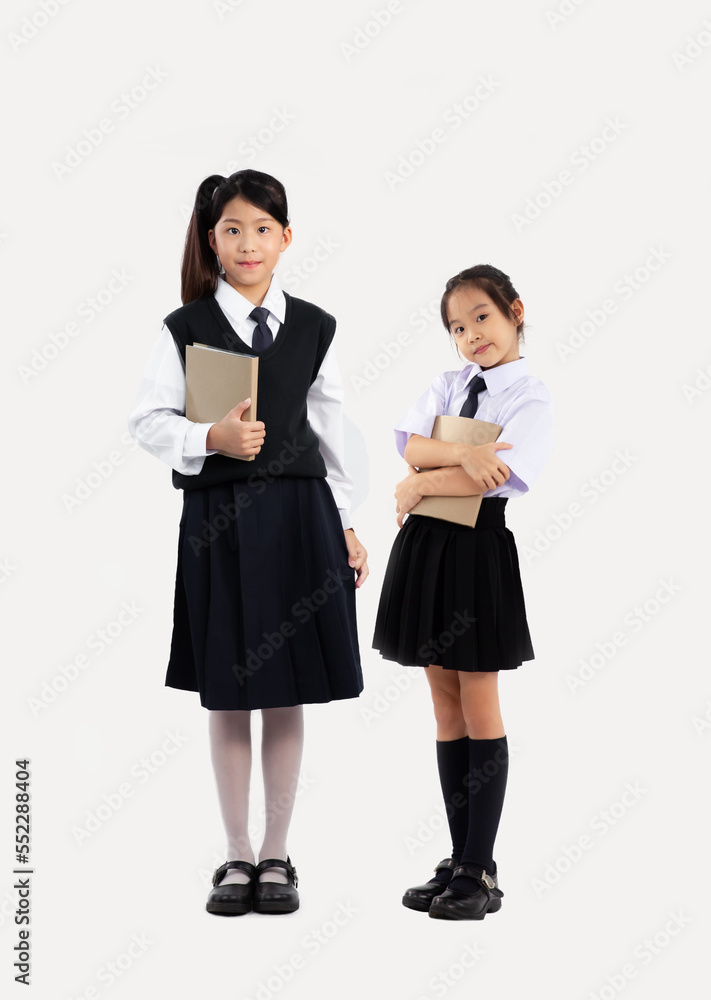 Asian girls junior student in school uniform holding book standing full length white background. Asian girls junior student in school uniform holding book standing full length white background.