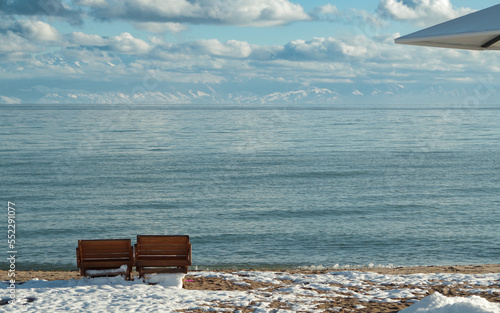 Sun loungers on a snow-covered beach against the backdrop of mountains