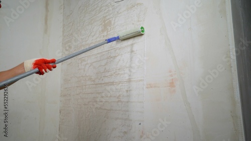 The process of applying a primer to a wall using a roller. The primer solution is applied to the wall using a roller, so as to remove dust and increase adhesion. Primer treatment. 