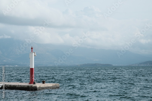 lighthouse on the seashore, sky with clouds and mountains on the horizon