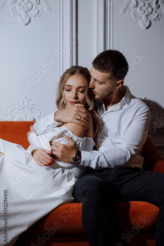 Close-up of a Caucasian couple, stylish and elegant on a white background, sitting on a red sofa