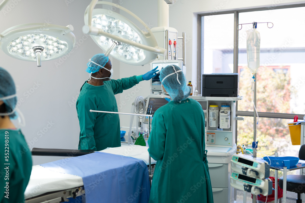 Obraz premium Diverse group of surgeons ready for surgery checking equipment in operating theatre before operation