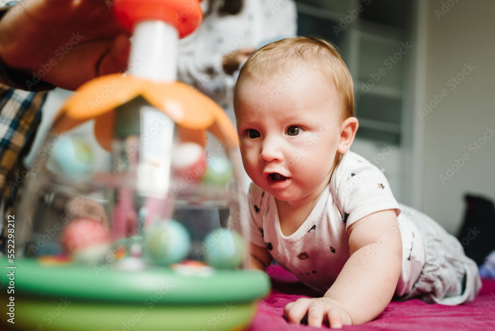 Obraz premium Portrait of baby a crawling to toys on bed in room. Adorable baby boy in bedroom. Newborn child playing. Nursery for children. Family morning at home.