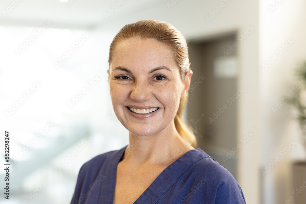 Portrait of smiling caucasian female healthcare worker in hospital corridor, with copy space Portrait of smiling caucasian female healthcare worker in hospital corridor, with copy space