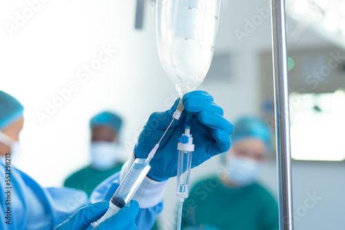 Wall Mural Gloved hand of surgical tech preparing iv fluid bag in operating theatre, with c