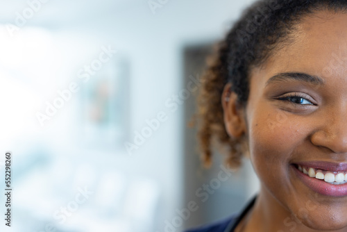Half face portrait of smiling african american female doctor in hospital corridor, with copy space photo