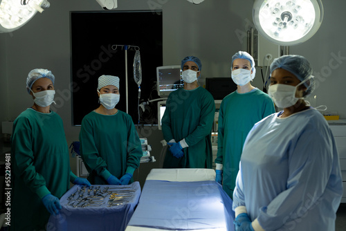Diverse team of surgeons and techs ready for operation, standing around operating table in theatre