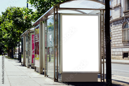 bus shelter at a busstop. glass and steel frame structure. blank white billboard ad display. empty lightbox sign. city transit station. urban street setting. advertising concept. outdoor scene