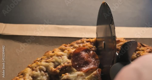 Italian Style Pepperoni Pizza Cutiing with Pizza Cutter POV hand photo