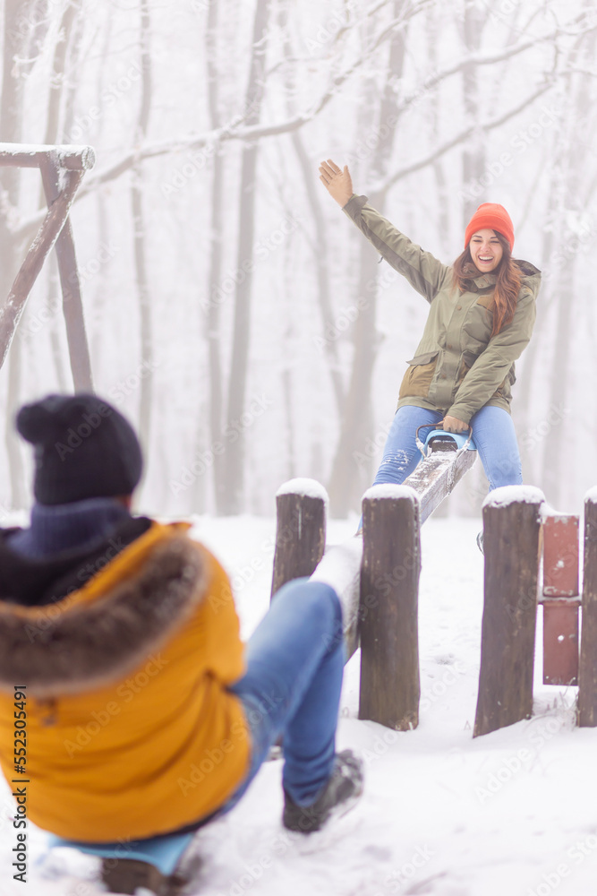 Couple having fun playing on seesaw while on winter vacation