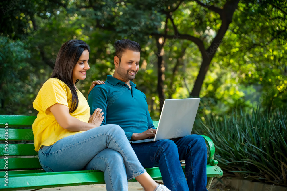 Young indian couple using laptop at park. Young indian couple using laptop at park.
