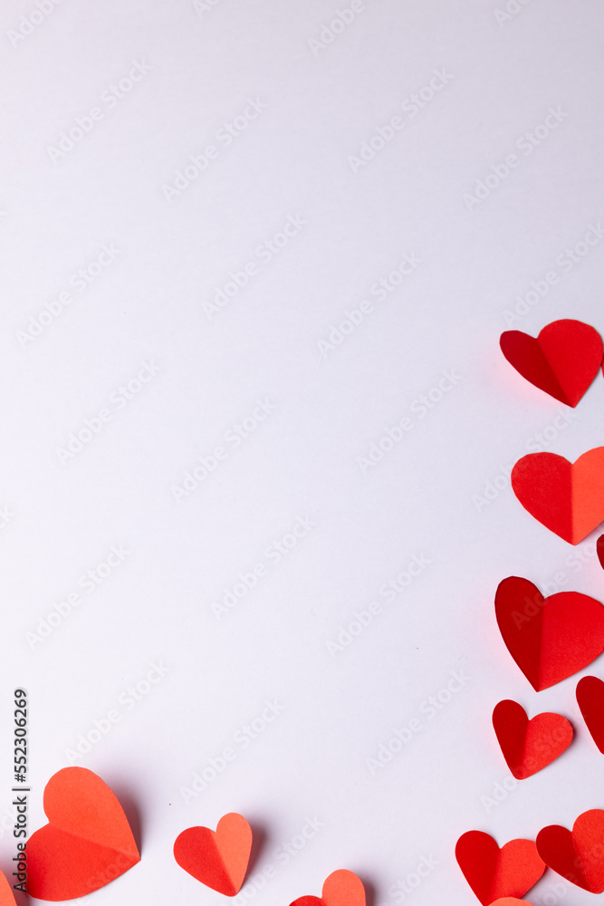 Vertical image of red paper heart shapes on white background with copy space