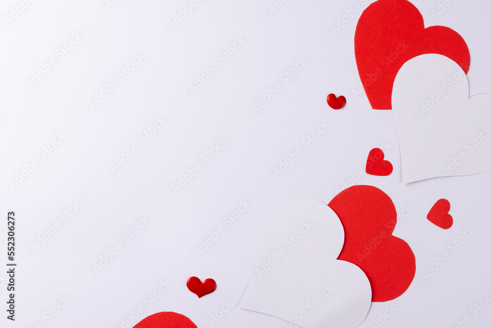 Red and white paper heart shapes on white background with copy space