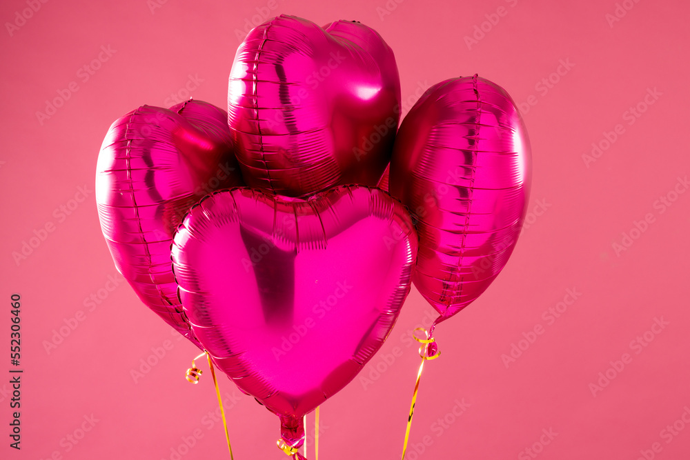 Four shiny pink heart shaped balloons floating on pink background with ...