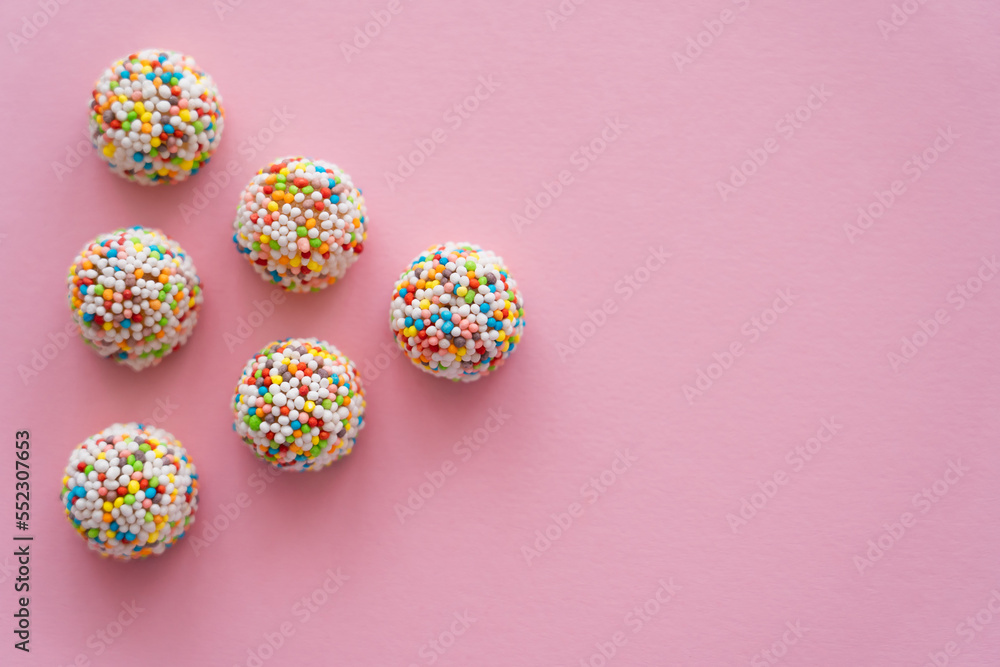 Flat lay of tasty candies with copy space on pink background.