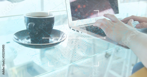 A woman using a laptop with a coffee cup on a table in a restaurant photo