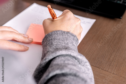 Close-up of a hand writing it on a posit