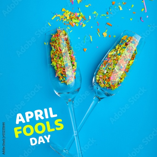 Composition of april fools day text over champagne glasses with confetti