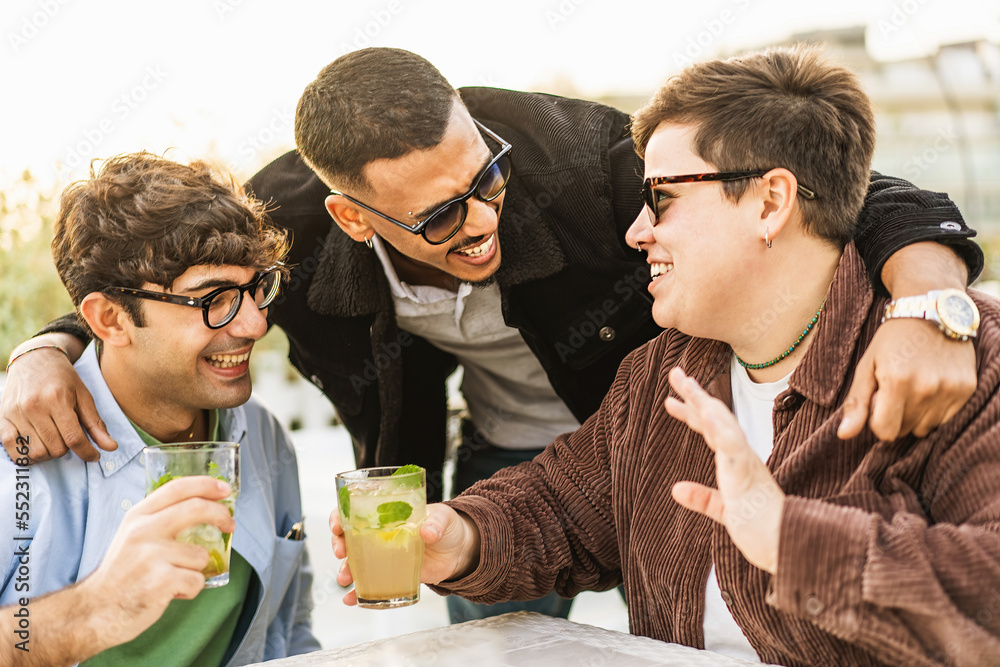 Diverse group of friends having fun drinking mojito cocktails and talking together meeting at the outdoor pub Diverse group of friends having fun drinking mojito cocktails and talking together meeting at the outdoor pub