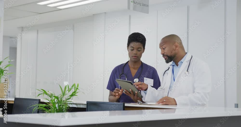 African american male and female doctors using tablet, talking at hospital African american male and female doctors using tablet, talking at hospital