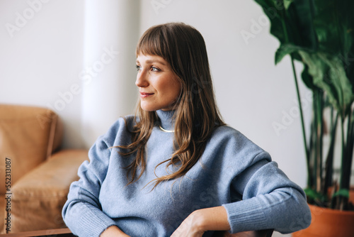 Foto Young businesswoman looking away thoughtfully in a modern office