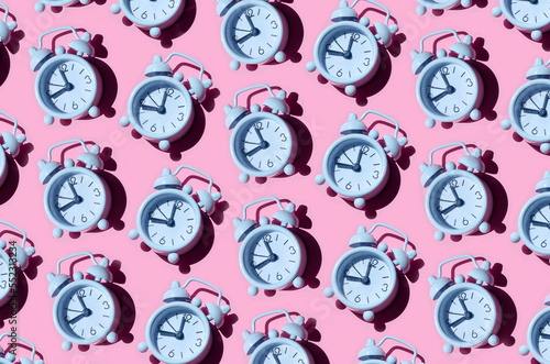 Seamless pattern of old white alarm clocks on pink background