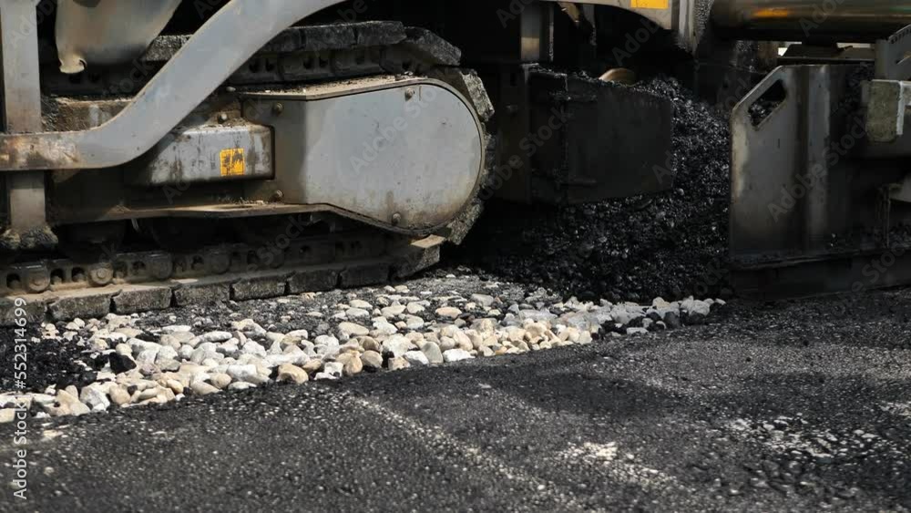 Asphalt spreader or asphalt paver on a road construction site close-up. Asphalt spreader or asphalt paver on a road construction site close-up.