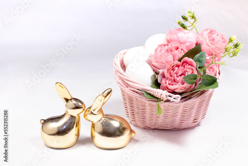 two golden rabbits behind white background with flowers