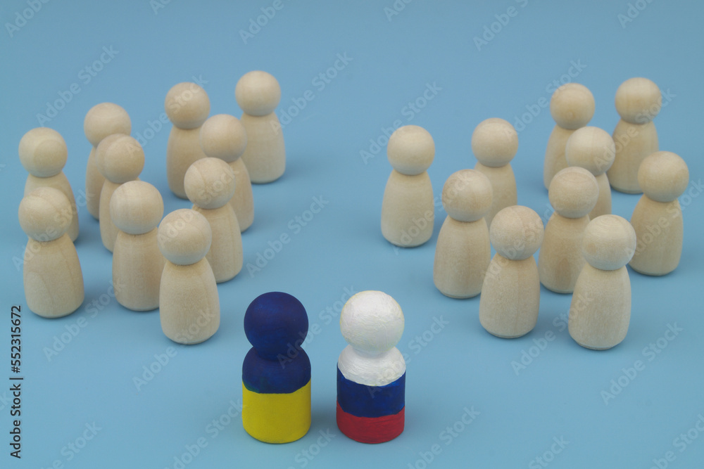 Wooden people figures are divided into two parts, and leaders is painted in colors of Ukrainian and Russian flags. Agreement between Russia and Ukraine, stopping hostilities and making  peace concept.