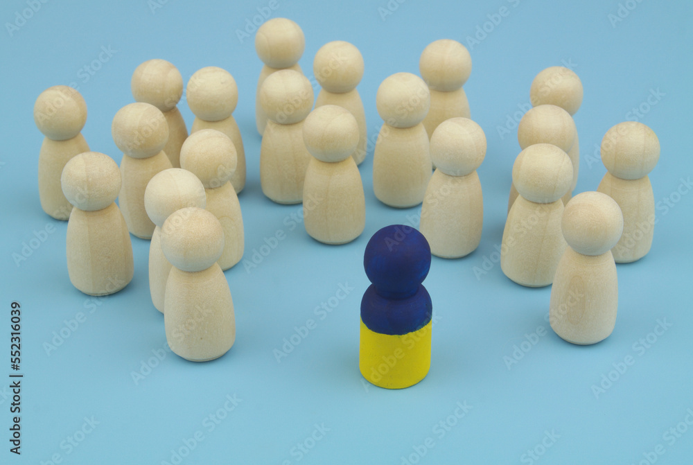 One leader with colors of Ukrainian flag and wooden people figures on blue background, One leader with colors of Ukrainian flag and wooden people figures on blue background,